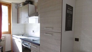 Een kleine keuken met een spoelbak, fornuis en kastjes.
