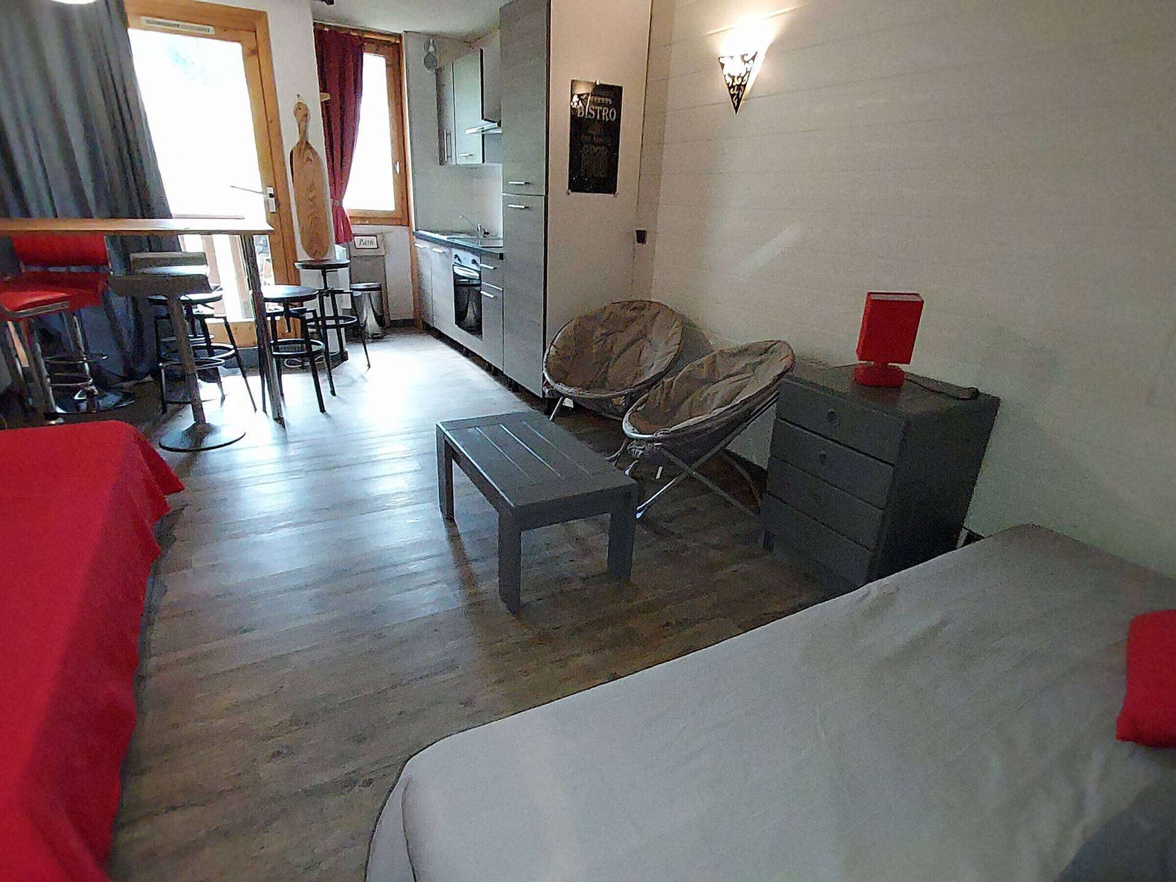 Ein kleines Hotelzimmer mit Bett, einem Tisch, einem Stuhl und einer Küchenzeile.