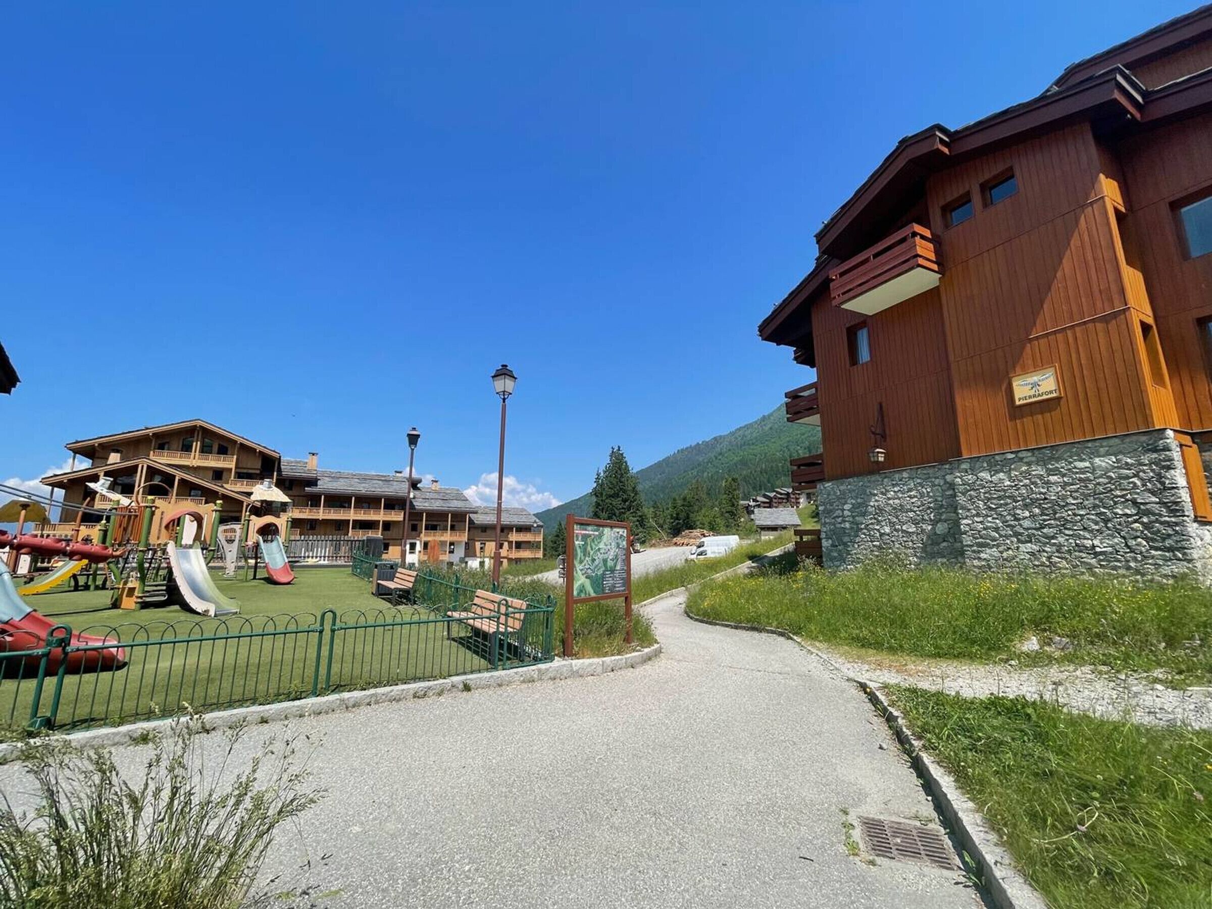 A ski resort with wooden buildings, a playground, and a clear sky.