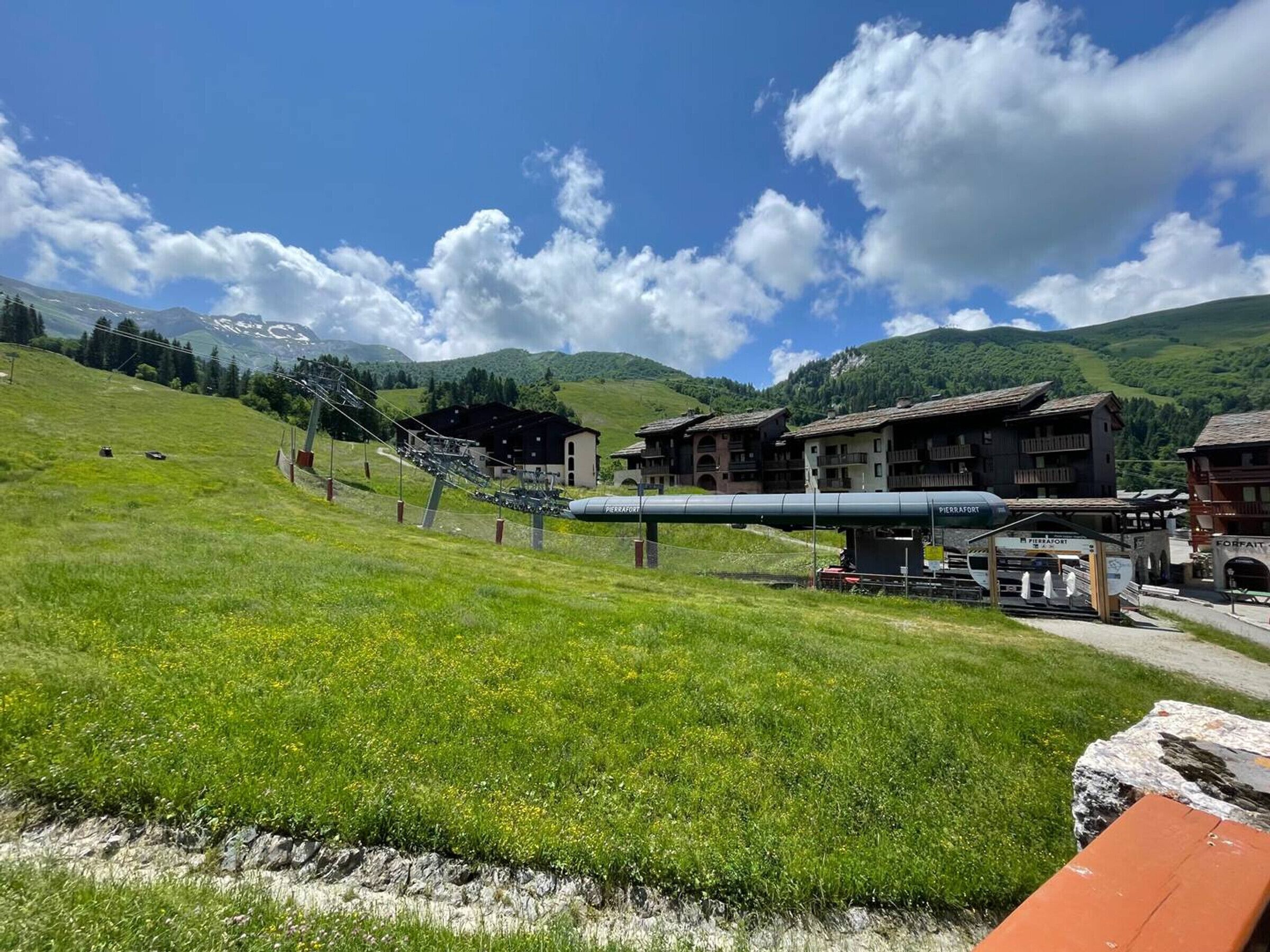 A mountainous landscape with a ski lift, buildings with balconies, and a clear sky.