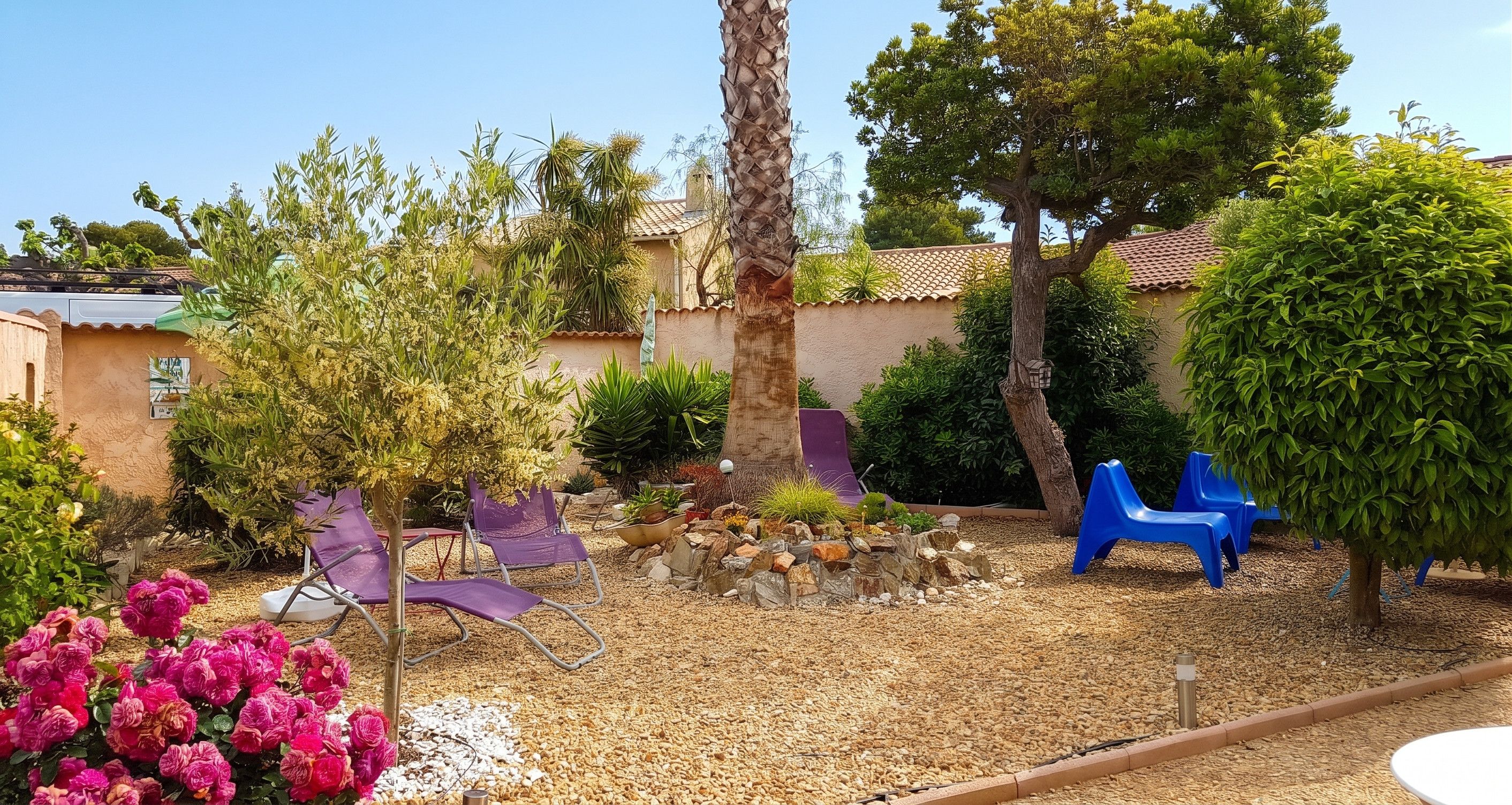 Un jardin agrémenté de diverses plantes, d’un palmier et de mobilier d’extérieur.