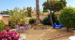 A garden with a variety of plants, a palm tree, and outdoor furniture.