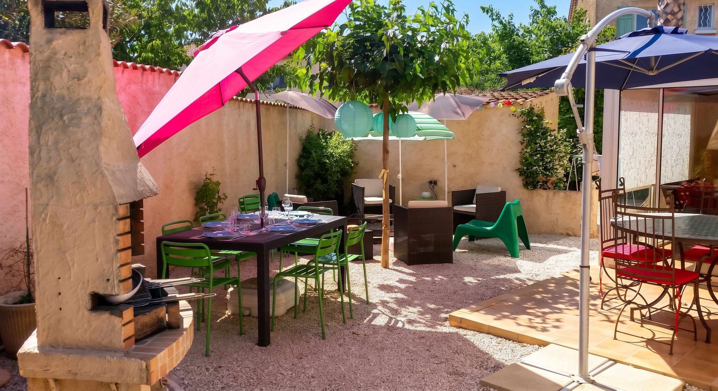 Eine Terrassenfläche im Freien mit Esstisch und Stühlen, umgeben von Sonnenschirmen.