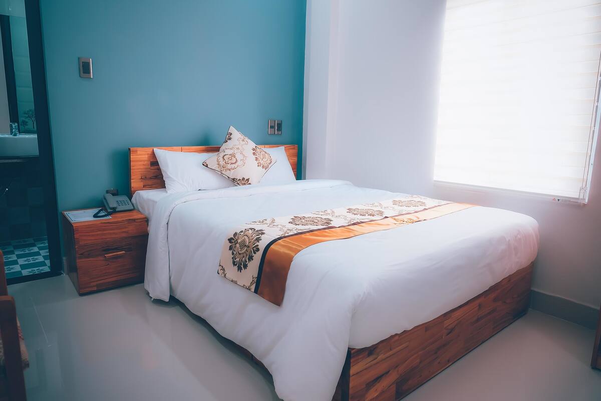 A neatly made bed with a wooden headboard, white bedding, and a decorative throw.