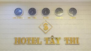 Un mur orné d’horloges indiquant l’heure de différentes villes, avec l’inscription « HÔTEL TAY THI ».