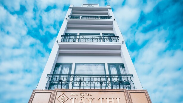 Un hôtel appelé « MINI HOTEL TAY THI », avec une façade blanche et des balcons.