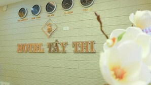 Un mur orné d’horloges indiquant l’heure de différentes villes, avec l’inscription « HÔTEL TAY THI ».