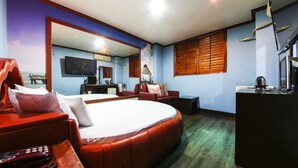 A hotel room with a large bed, a desk, a TV, and a view of the sea through the window. - Swiss Motel (Seoul)