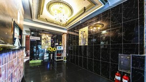 A lobby with a marble floor, a reception desk, a chandelier, and a wall with framed artwork. - Swiss Motel (Seoul)