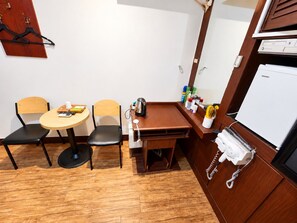 A compact room with a wooden table, two chairs, a small kitchenette, and a white refrigerator. - Hotel Swiss  (Seoul)