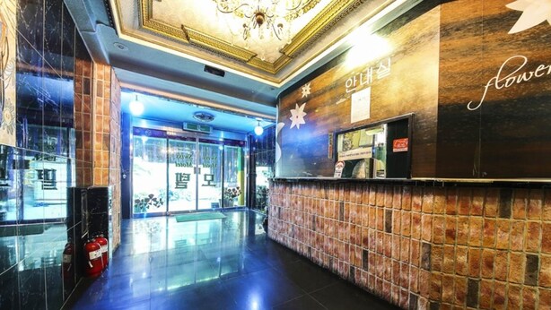 A lobby with a polished floor, a reception desk, and a wall with a floral pattern. - Swiss Motel (Seoul)