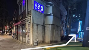 A building with a sign for a tattoo studio, a paved sidewalk, and a directional arrow on the ground. - Swiss Motel (Seoul)