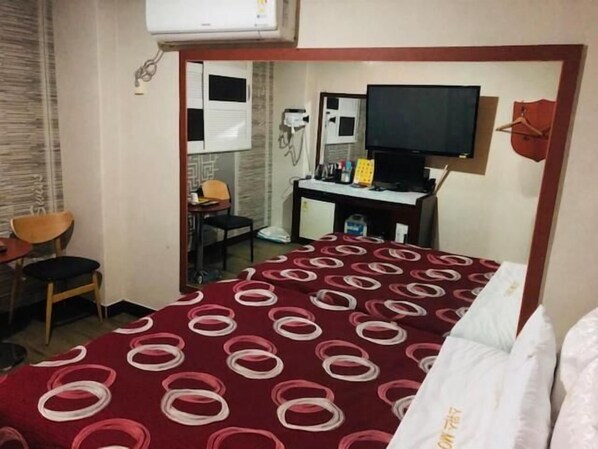 Une chambre d’hôtel équipée d’un lit, d’un bureau, d’une chaise, d’une télévision et d’un miroir.
