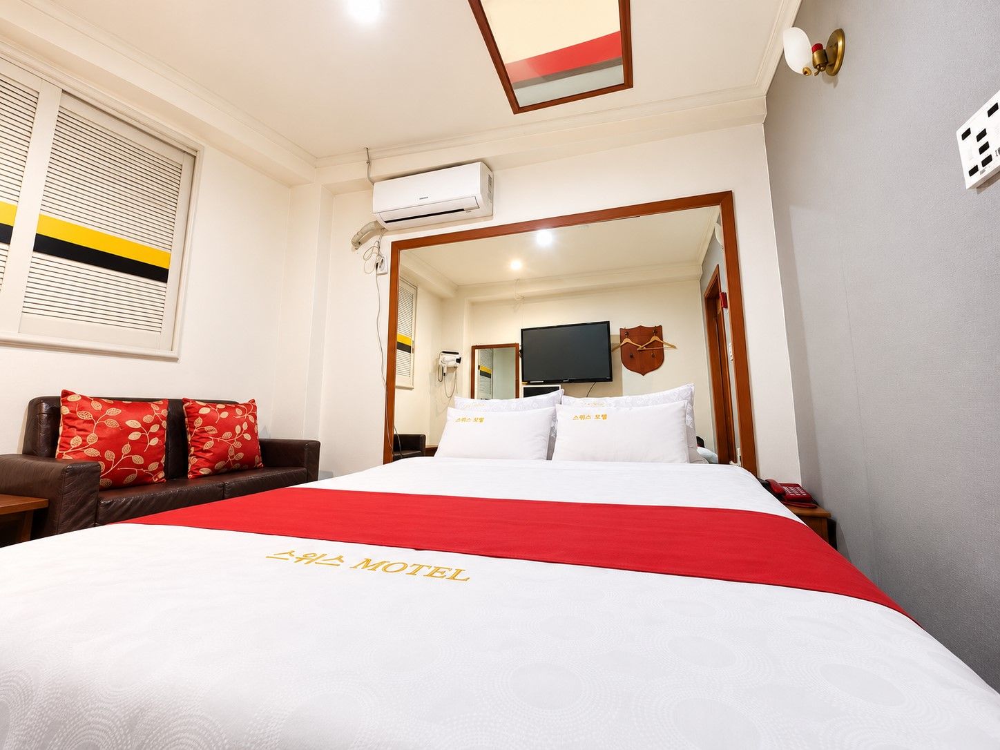 Una habitación de hotel con una cama, televisión y ventana con persianas.
