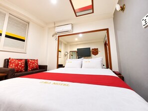 Une chambre d’hôtel avec un lit, une télévision et une fenêtre équipée de stores.