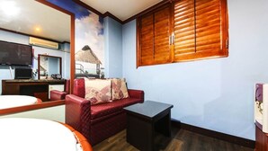 A room with a red sofa, a small table, a wooden cabinet, a TV, and a mural of a mountain and beach. - Swiss Motel (Seoul)