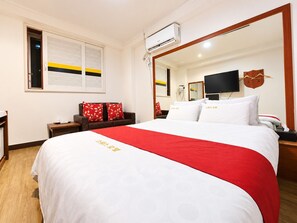 A hotel room with a large bed, a flat-screen TV, a mirror, and a window with blinds. - Hotel Swiss  (Seoul)