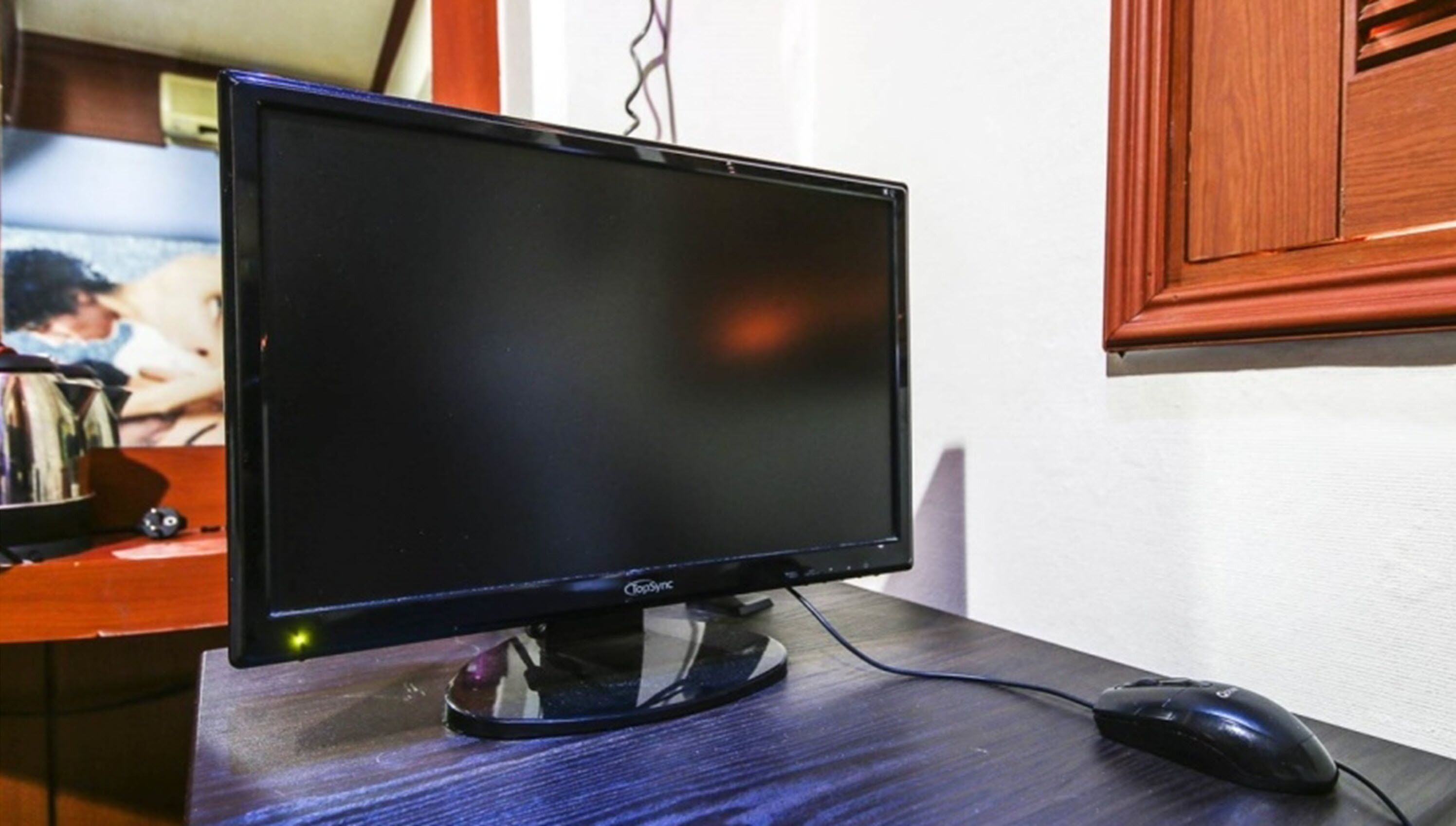 Monitor de tela plana sobre uma mesa de madeira com um mouse de computador.