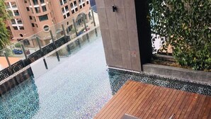 A rooftop pool with a wooden deck and lounge chairs. - Gallipoli Anggun Suites (Kuala Lumpur)