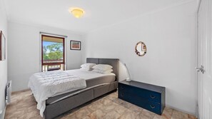 Une chambre à coucher avec un lit, une table de chevet et une vue sur l’extérieur.