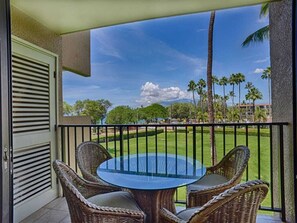 Relax on the balcony with a round table and two wicker chairs, taking in the serene views of the lawn and distant building complex.