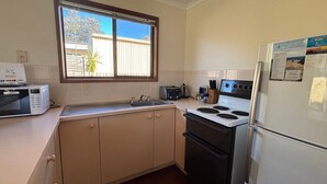 Eine kompakte Küche mit Mikrowelle, Toaster, Spüle, Herd und Kühlschrank.