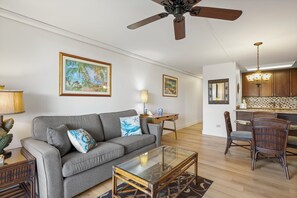 A living room with a sofa, coffee table, and a dining area with chairs and a table.