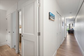 A hallway with white doors, a wooden floor, and a sign on the wall. - 1 Bedroom w/Modern Kitchen - Kamaole Sands 6206 (KIHEI)