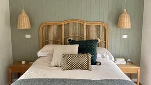 Ein Bett mit Holz-Kopfteil, zwei Nachttische und zwei Pendelleuchten.