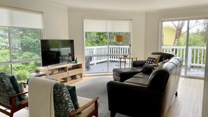 Ein Wohnzimmer mit Fernseher, einer Couch, einem Sessel und einem Bücherregal.