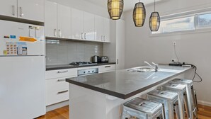Una cocina moderna con armarios blancos, una isla de acero inoxidable y un ventanal sobre el fregadero.