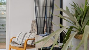 Una sala de estar moderna con una silla de madera, un sofá a rayas negro y blanco, y una planta grande en maceta.