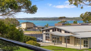 Una zona residencial costera con casas modernas, vistas despejadas del mar y un paisaje montañoso al fondo.