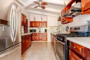 A kitchen with wooden cabinets, stainless steel appliances, and a tiled backsplash. - Golf Villa 70 - Casa de Campo - Lake and Golf View- Maid Cook Wifi - Near Beach (La Romana)