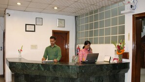 Una reception con piano di marmo, una sveglia appesa al muro e certificati incorniciati.