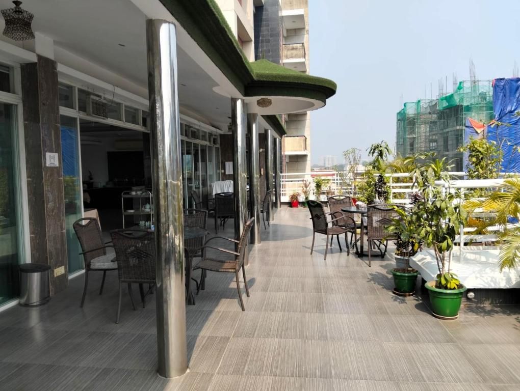 A rooftop terrace with outdoor seating, potted plants, and a view of a construction site in the background.