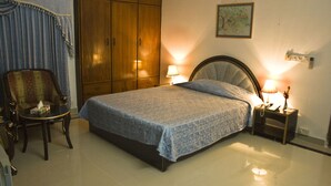 A bedroom with a bed, a nightstand, a chair, and a wardrobe. - Aristocrat Inn (Dhaka)