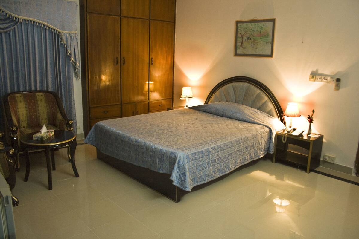 A bedroom with a bed, a nightstand, a chair, and a wardrobe.
