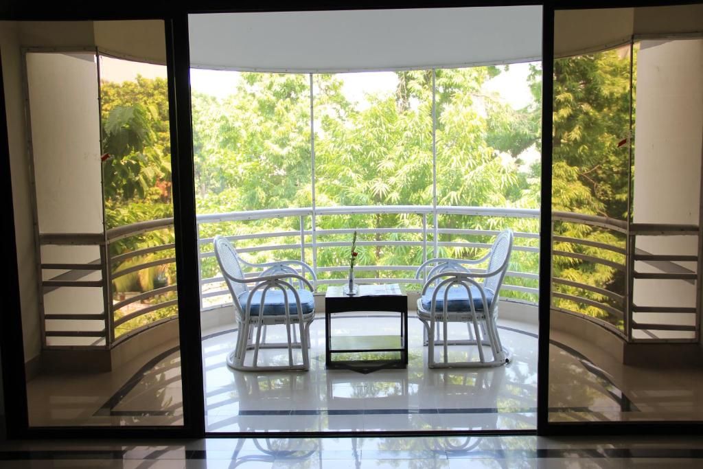 A balcony with two chairs and a table, overlooking a lush green landscape.