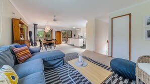 A modern living room with a sofa, a coffee table, and a dining area with chairs. - Florida Trees - Wifi Incl (INVERLOCH)