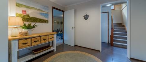 A hallway with a wooden console table, a rug, and a staircase leading to another room.