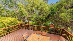 A wooden deck with a table and chairs, surrounded by lush greenery and trees. - Florida Trees - Wifi Incl (INVERLOCH)