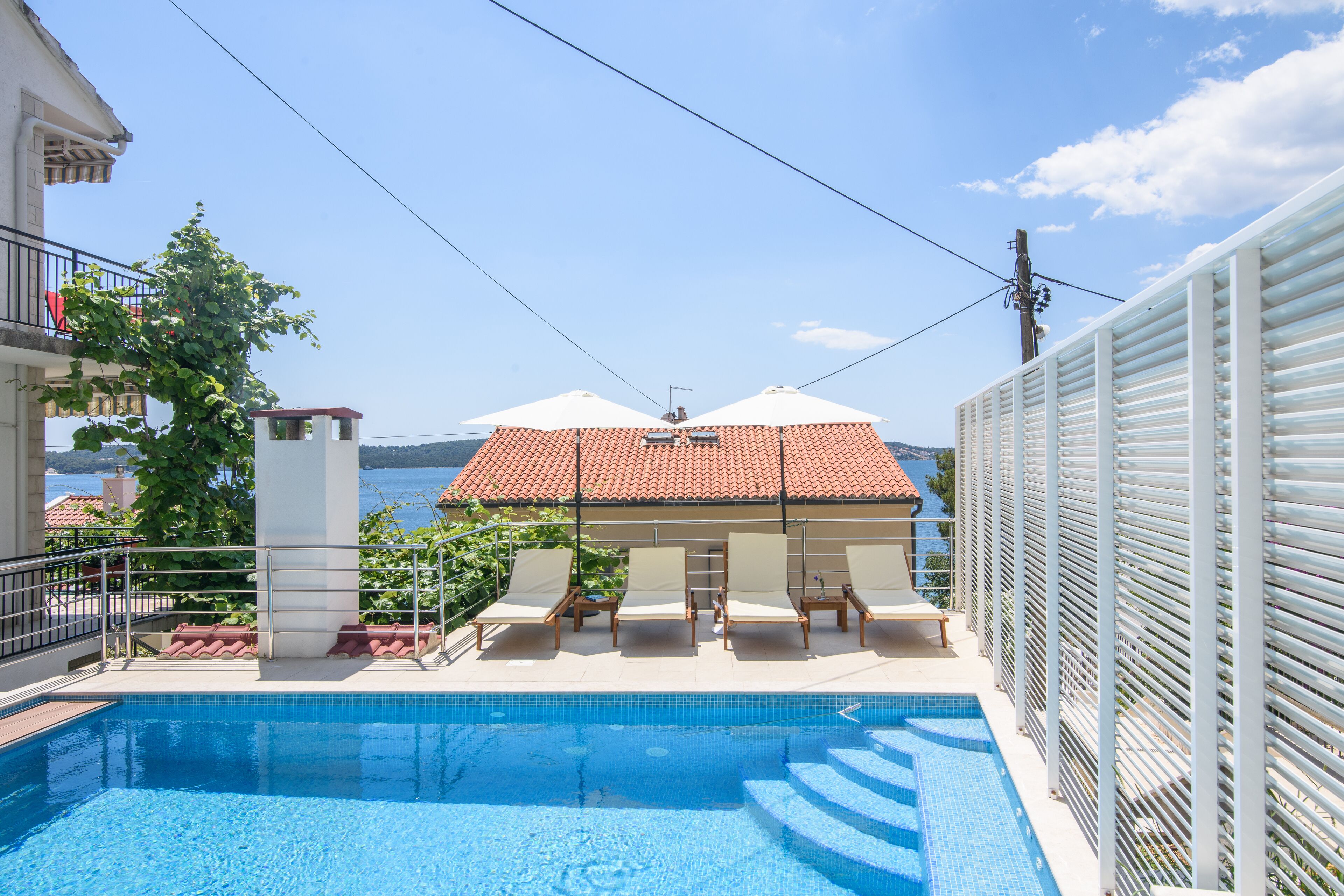 A swimming pool with lounge chairs and a view of the sea.