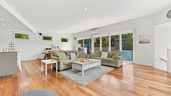 A spacious living area with a kitchen, a dining table, and a sofa set.