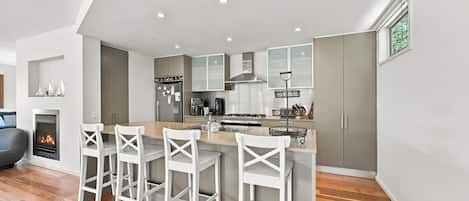 A modern kitchen with a central island, bar stools, and a built-in stove.