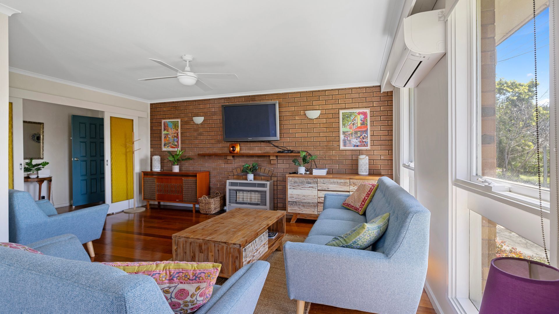 A living room with a brick wall, a flat-screen TV, and a large window.