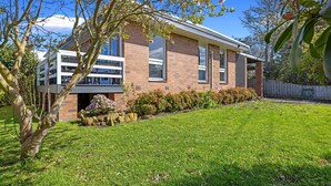 A modern two-story house with a brick facade, large windows, and a well-maintained lawn.