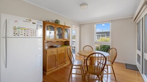 A kitchen with wooden cabinets, a refrigerator, and a dining table with chairs.
