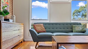 A living room with a grey sofa, a wooden coffee table, and a rustic wooden dresser.