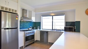 A modern kitchen with stainless steel appliances, a dishwasher, and a window providing natural light. - Plovers Rest Inverloch (INVERLOCH)